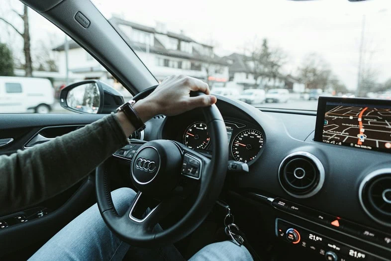 A driver's hands on the wheel on an open road